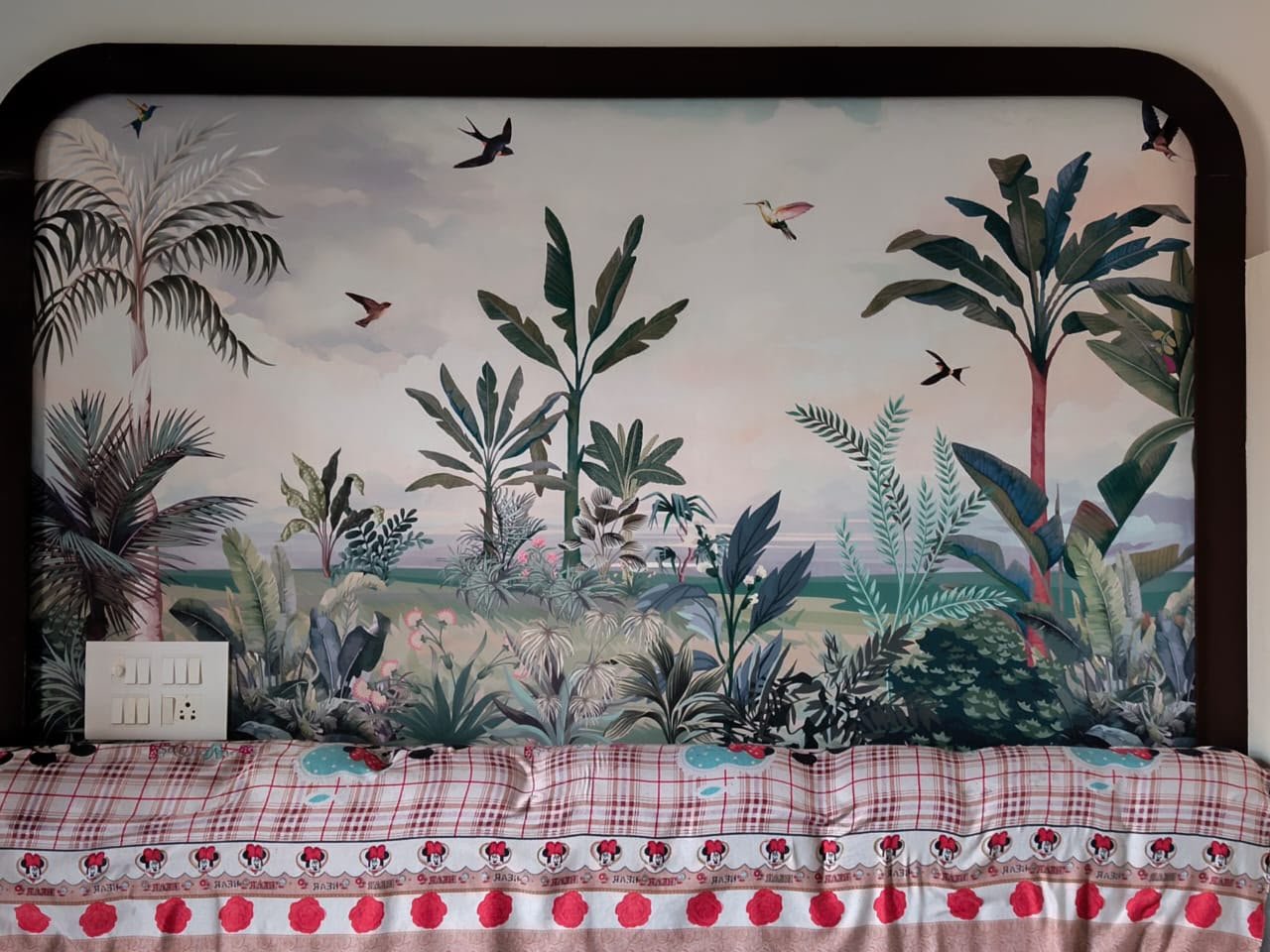 Tropical mural wallpaper behind a bed